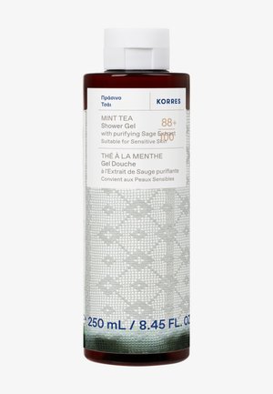 Ruskea pullo Korres Mint Tea -suihkusaippuaa, jossa on tekstuurinen harmaa etiketti, jossa on valkoista tekstiä ja sinisiä yksityiskohtia. Tilavuus on 250 mL.