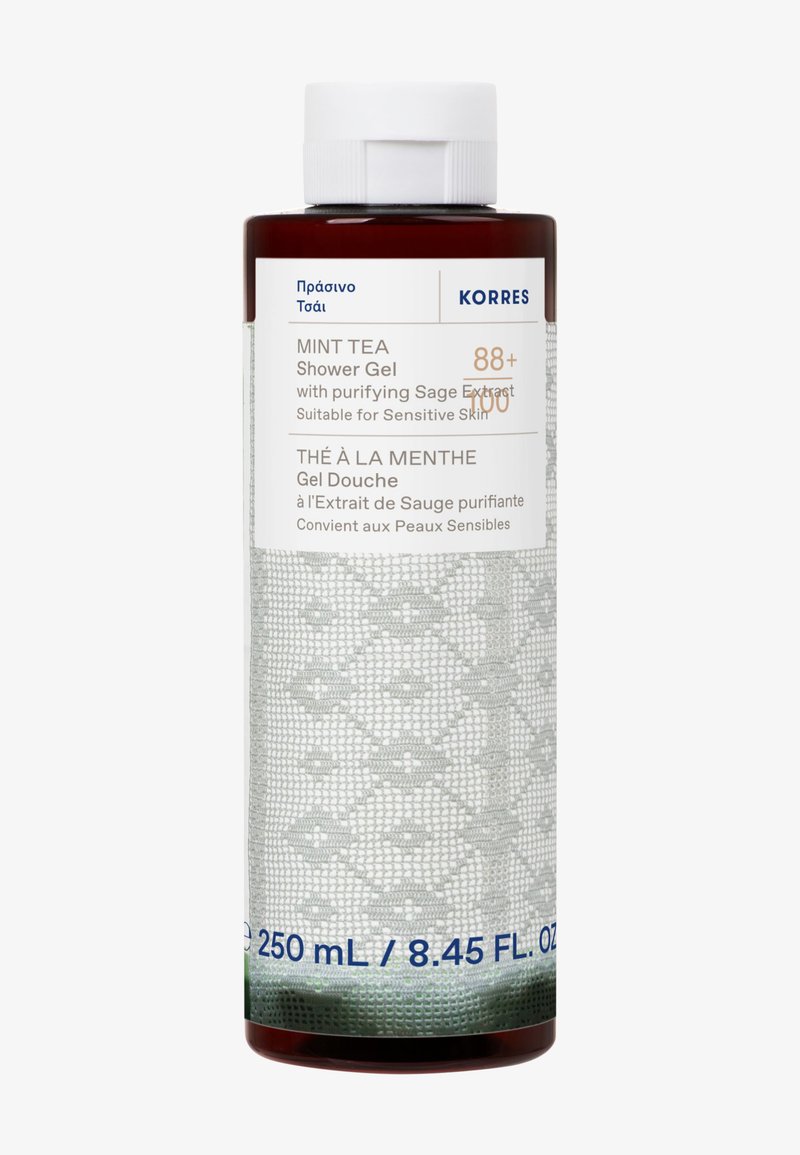 Brązowa butelka żelu pod prysznic Korres Miętowa Herbata z teksturowaną szaro-skalną etykietą, z białym napisem i niebieskimi akcentami. Pojemność wynosi 250 ml.