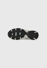 Suela de goma negra con un patrón texturizado, que presenta acentos blancos y un tacón redondeado. Diseñada para ofrecer agarre y estabilidad.