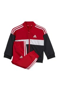 Chándal rojo y negro con chaqueta con cremallera, franja blanca y pantalones negros. Hecho de material suave, con puños acanalados y un logo de Adidas.