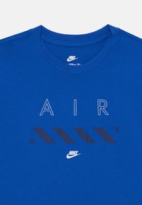 Mėlynas medvilnės marškinėliai su žodžiu "AIR" baltu tekstu ir tamsiai mėlynomis horizontaliomis juostelėmis, apačioje esantis mažas Nike logotipas. Apvalus iškirpimas.