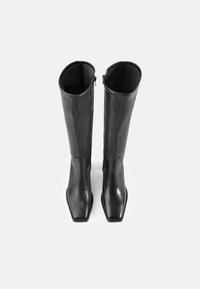 Bottes noires en cuir montant jusqu'au genou avec un bout carré arrondi et une texture lisse. Dotées d'une fermeture éclair sur le côté pour un enfilage facile.