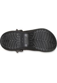 Fond de sabot Crocs noir avec une semelle en caoutchouc texturé présentant un motif en zigzag et des grips circulaires. Marque "Crocs" bien visible.