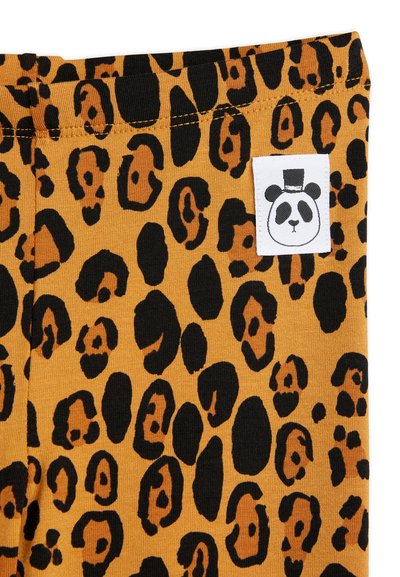 Leopardmönstrad tyg i nyanser av orange och svart med en panda-logotyp på midjan. Slät textur, flexibelt material.