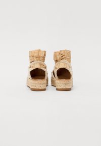 Karamelli espadrilli sandaalid, millel on kootud disain ja platvorm. Raadiosa on tekstuuriga kangast pahklööt, mille taga on lipsu detail.