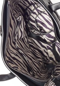 Czarna torba na ramię z wnętrzem wyłożonym w zebrze w odcieniach beżu i ciemnej purpury. Zawiera liczne kieszenie oraz zamek błyskawiczny.