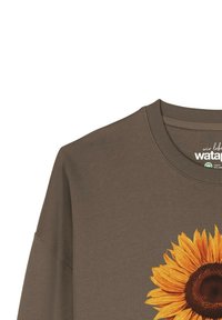 Bruine katoenen sweatshirt met een grote, levendige zonnebloemafbeelding op de voorkant, met gedetailleerde bloembladen en een centraal donker zaadpatroon.