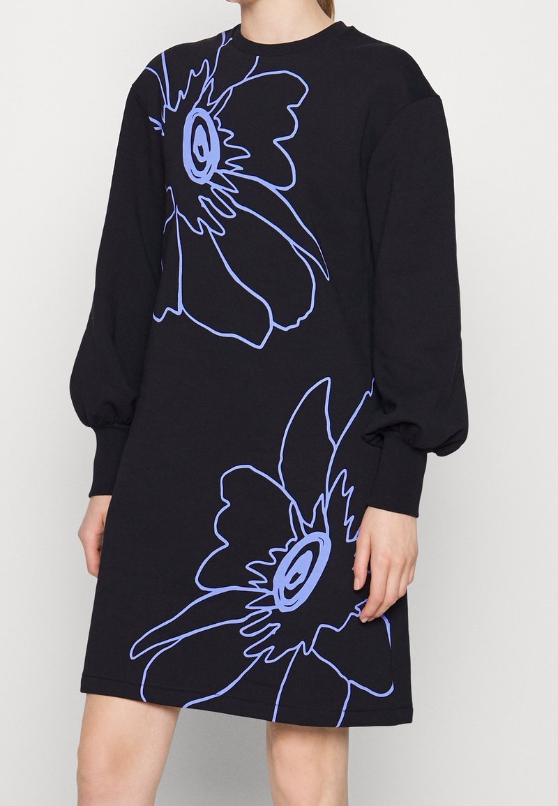 Abito felpa nero con maniche lunghe a palloncino. Presenta un contorno di grandi fiori blu sul davanti. Realizzato in un materiale morbido.