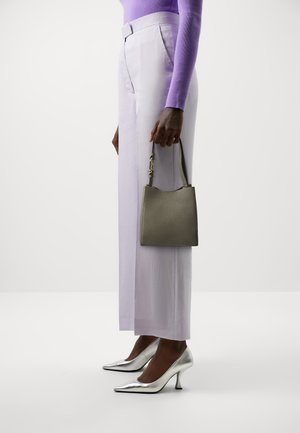 Small textured olive green handbag with a curved top, held in one hand. Paired with lavender tailored wide-leg pants and silver pointed heels.