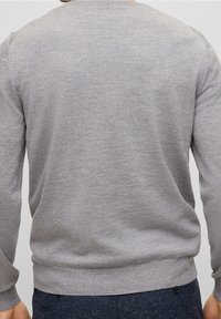 Pull en tricot gris avec des manches longues et un col rond. Texture lisse avec une bordure ajustée, présentant des détails subtils en côtes.