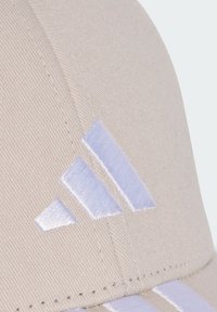 Beige cap featuring a textured fabric, accented with a white embroidered three-stripe logo on the front. Stitched detailing visible.