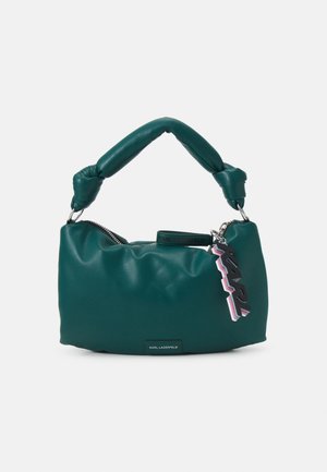 Bolso acolchado color azul verdoso con asa anudada, cremallera plateada y etiqueta de llavero KARL colorida sobre fondo blanco.