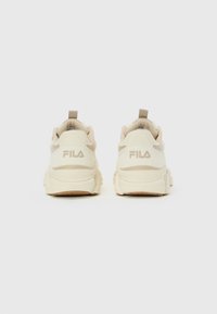 Bakside av et par off-white FILA-sneakers med tykke såler på en ensfarget hvit bakgrunn.