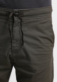 Mørkegrønne, letvægts shorts med tekstureret stof, der har en elastisk talje og snøre for justerbar pasform.