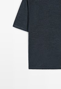 Dunkelgrauer Strickstoff mit Kurzarm und feiner Textur, zeigt Ärmel- und Seitenkantenrand vor weißem Hintergrund.