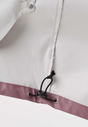 Close-up of a light gray fabric panel with a mauve trim showing a black adjustable cord lock and grommets on the edge.