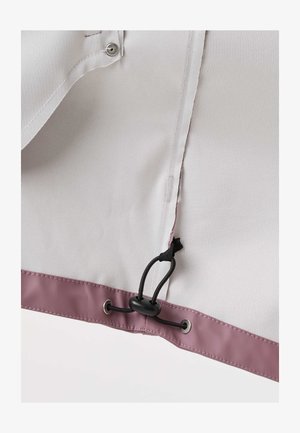Close-up of a light gray fabric panel with a mauve trim showing a black adjustable cord lock and grommets on the edge.
