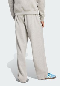 Gray cotton sweatpants with an elastic waistband, relaxed fit, and smooth texture, paired with light blue sneakers featuring yellow stripes.