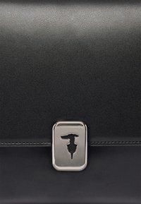 Svart läderväska med en texturerad yta. Har en silverfärgad metallspänne med en utskuren design. Horisontell sömnad över framsidan.