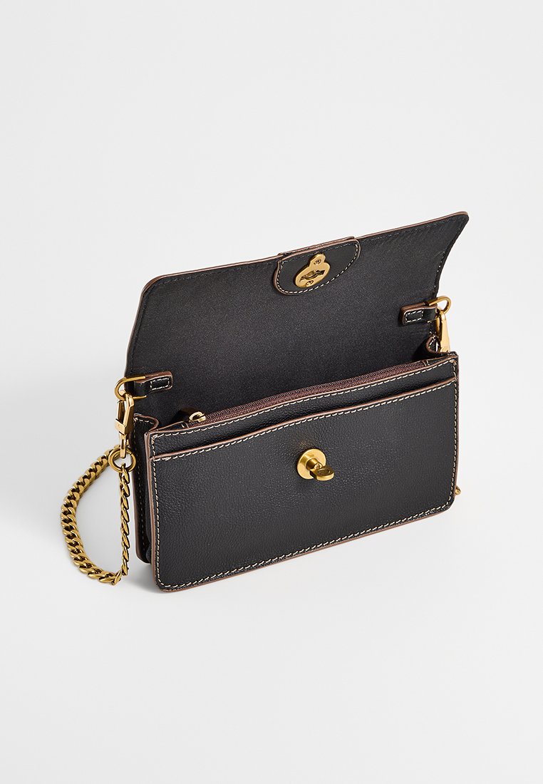 Sac en cuir noir avec quincaillerie dorée, bandoulière en chaîne et détails de couture contrastants. Le design ouvert révèle deux compartiments avec une poche zippée.