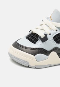 Light blue and black sneaker with mesh detailing, white laces, rubber sole, and textured accents. Features a rounded toe and structured design.
