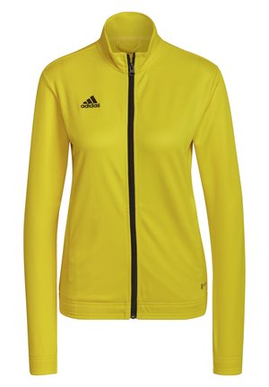 Gele zip-up jas met lange mouwen, zwart Adidas-logo op de linkerborst en een hoge kraag, getoond op een witte achtergrond.