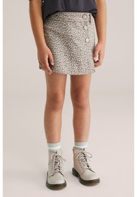 Gonna mini in denim con stampa leopardata, dotata di tre bottoni frontali; abbinata a stivali grigi con lacci e calze grigie a righe.