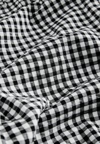 Tissu à carreaux noir et blanc avec de petits carrés, légèrement froissé et plié, montrant les détails de la texture et du motif.