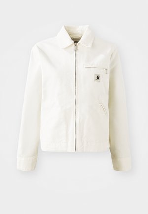 White jacket made of cotton with a zip front, pointed collar, and side pockets. Features a small logo patch on the chest and long sleeves.