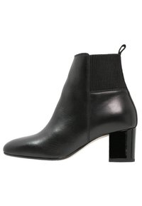 Bottines noires en cuir lisse avec un panneau élastique côtelé, un bout pointu et un talon épais et brillant.