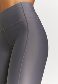 Šedé legíny vyrobené z hladké, elastické látky. Vysoký pas s plochými švy, který nabízí elegantní, přiléhavý design.