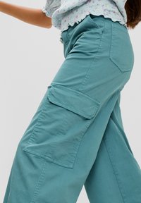 Lichtgroene cargobroek met een relaxed fit, voorzien van zijzakken, zachte stof en zichtbare stikseldetails op de benen.