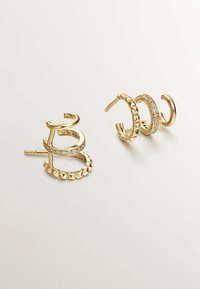 Pendientes de aro de oro que presentan tres diseños: un pendiente con un acento de cristal, una banda texturizada y un aro liso con forma de espiral.