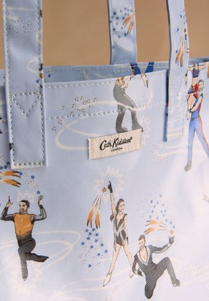 Svetlomodrá taška na rameno s ilustrovanými krasokorčuliarmi predvádzajúcimi triky, zdobená hviezdami a iskriacimi stopami, s nálepkou Cath Kidston London.