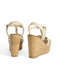 Witte wedge sandalen met kurkachtige hak, verstelbare band en een gladde afwerking. Heeft een ronde neus en een open achterontwerp.