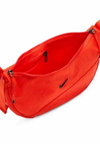 Marsupio in nylon rosso con zip superiore, tasche interne e un piccolo logo Nike nero sul davanti. Cinghia regolabile per una vestibilità sicura.