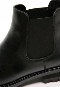 Czarne skórzane botki za kostkę z elastycznymi panelami bocznymi, gładką fakturą, okrągłym czubkiem oraz solidną gumową podeszwą z bieżnikiem.