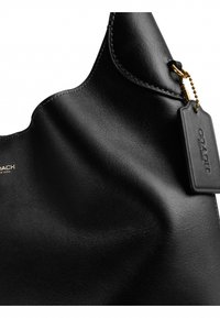 Sac Coach en cuir noir avec coutures visibles et une étiquette noire en cuir suspendue attachée par une chaîne dorée.