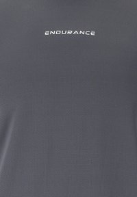 Harmaa urheilupaita, joka on valmistettu teksturoidusta kankaasta. Ominaisuuksina valkoinen "ENDURANCE"-logo rinnassa. Yksinkertainen, moderni muotoilu.