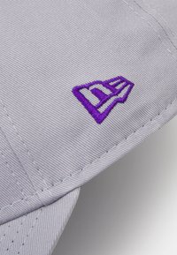 Gray cap with textured fabric and a curved brim. Features an embroidered purple logo on the side and visible stitching details.