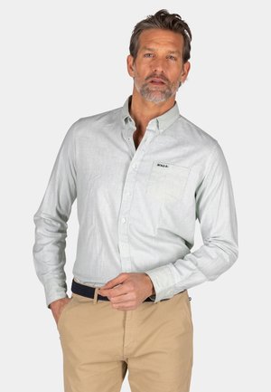  Lichtblauwe blouse met lange mouwen en knoopsluiting, textuurstof, borstzak en geborduurd logo, gecombineerd met beige broek.