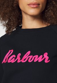 Sweat à capuche noir avec un lettrage brodé bold en rose "Barbour" sur la poitrine. Texture douce et design classique à col rond.