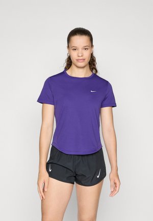 Camiseta deportiva morada de manga corta con cuello redondo y logo de Nike. Combinada con pantalones cortos negros con acentos de logo en blanco. Textura suave.