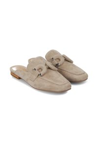 Zapatos tipo slip-on de ante beige con punta afilada, que presentan un lazo decorativo y acentos metálicos. Tacón bajo de madera, textura suave.