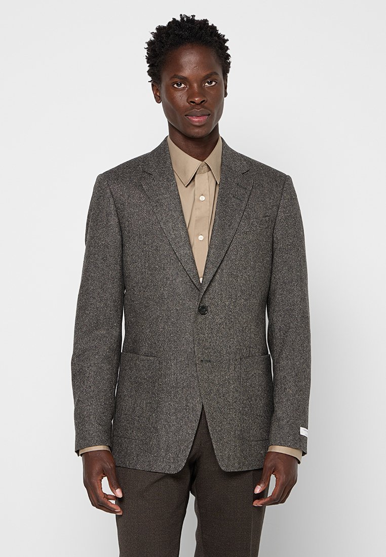 Grau kariertes Blazer mit Reverskragen, einreihiger Knopfverschluss, zwei vordere Taschen und strukturiertem Stoff, getragen über einem beigen Hemd.