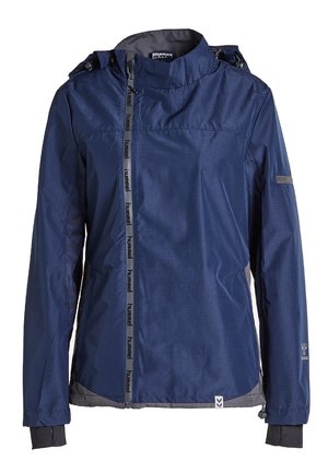 Marineblauwe waterdichte jas met capuchon, asymmetrische rits, duimmanchetten en subtiele merkslogo’s op de rits en mouw.