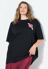 Overmaat zwart t-shirt van katoen, met een roze planeetafbeelding op de borst. Soepele textuur, ronde halslijn en korte mouwen.