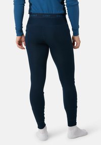 Leggings a coste di colore blu navy con un ampio elastico che riporta il nome del marchio. Il tessuto sembra elastico e aderente. Indossati con calzini bianchi alla caviglia.