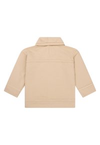 Beige Jacke mit einem kragenförmigen Halsausschnitt und langen Ärmeln. Der Stoff hat eine strukturierte Oberfläche und sichtbare Nähte entlang der Nähte.