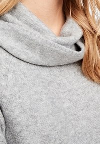 Maglione grigio chiaro con collo a drappo. Tessuto morbido e strutturato copre il collo e le spalle, caratterizzato da un design morbido.
